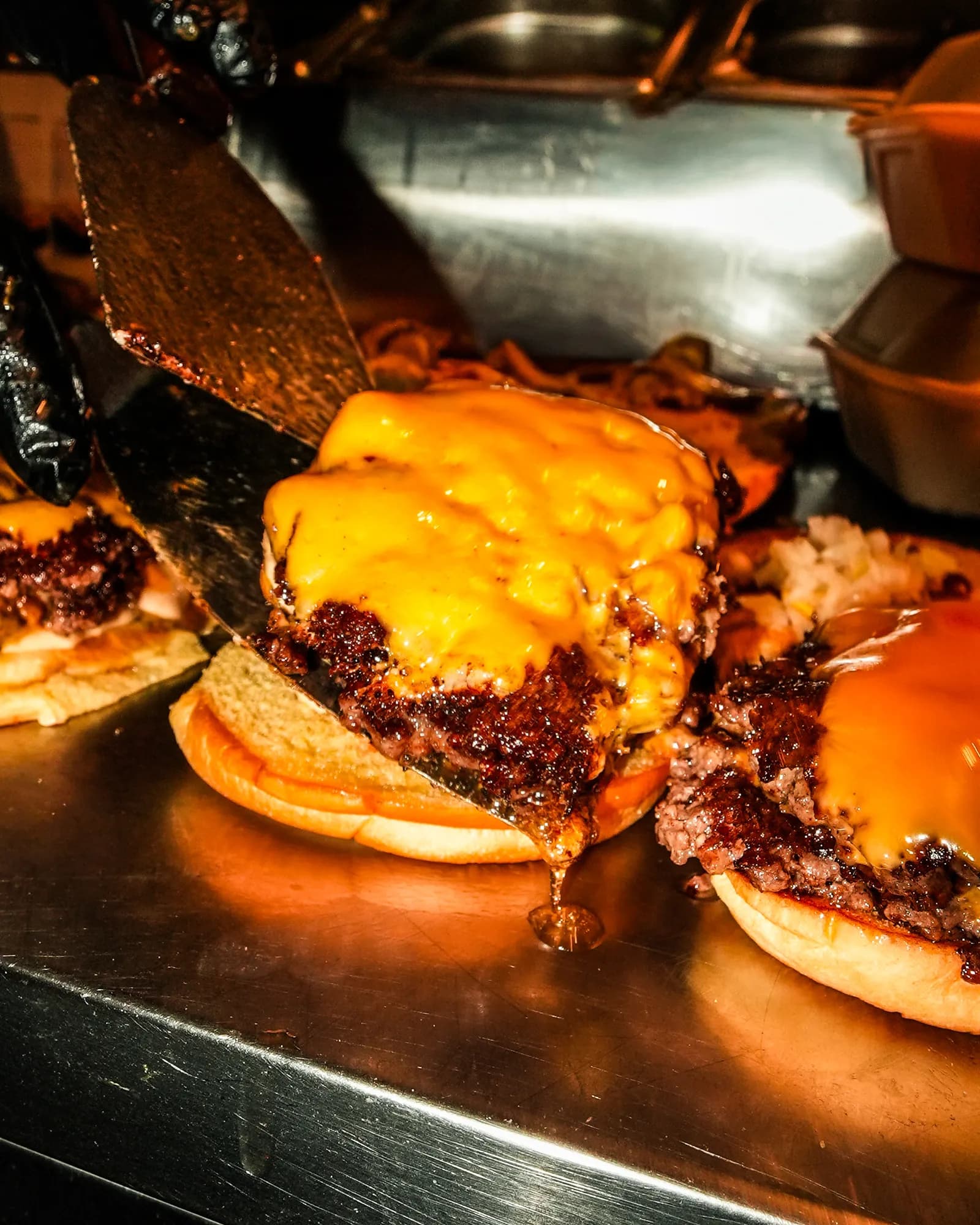 Smash Patty mit geschmolzenem Cheddar wird auf das Bun gehoben